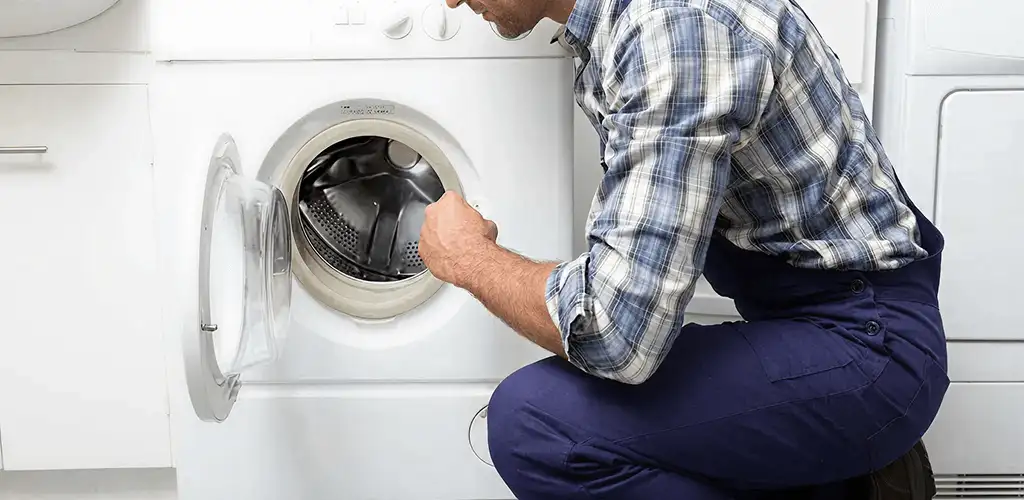 Handyman inspecting a dryer drum and internal parts for repair in Oklahoma City, OK