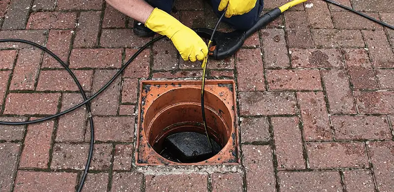Drain cleaning technician using a drain snake to clear a clogged drain in Oklahoma City, OK