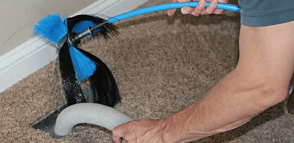 Dryer vent cleaning technician brushing lint from a vent line in Oklahoma City, OK