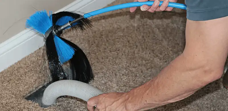 Dryer vent cleaning technician brushing lint from a vent line in Oklahoma City, OK
