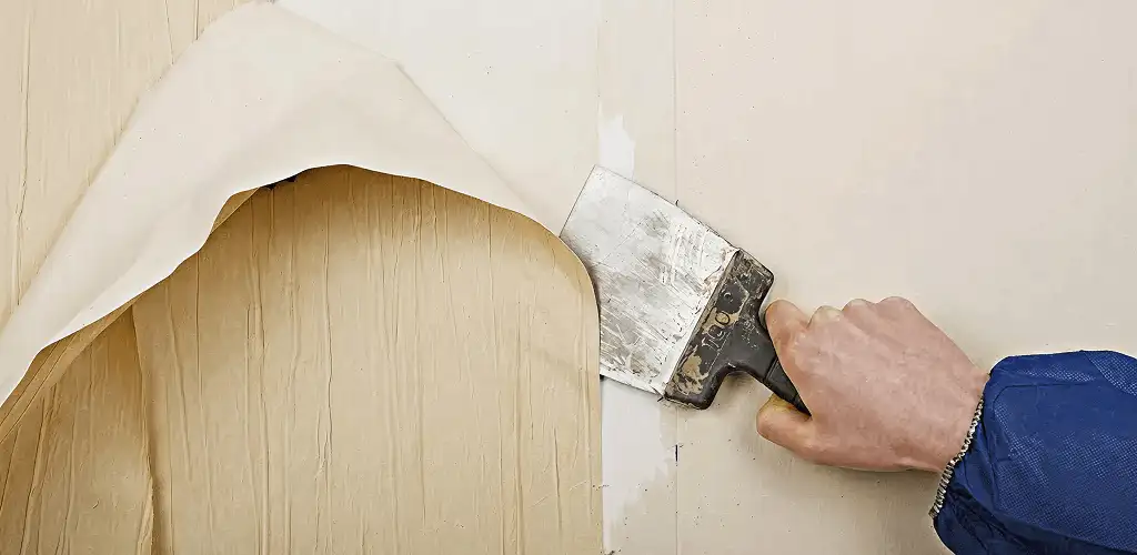Handyman removing wallpaper with a scraper for wall preparation in Oklahoma City, OK