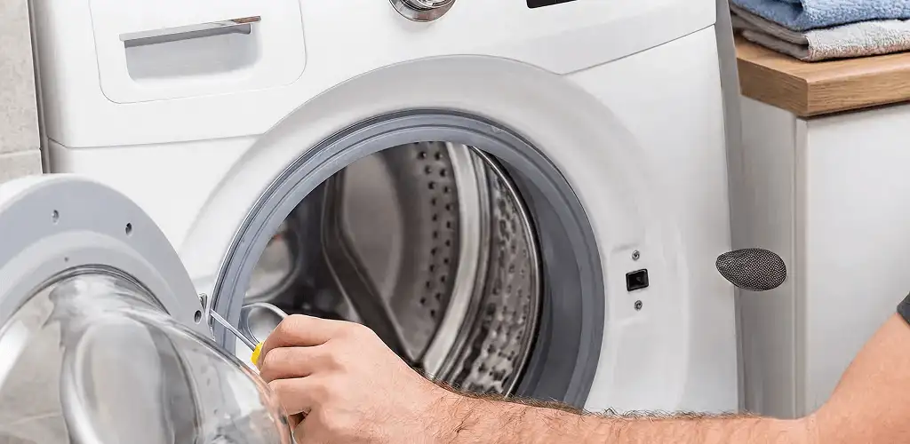 Handyman repairing a front-load washing machine and inspecting the drum in Oklahoma City, OK