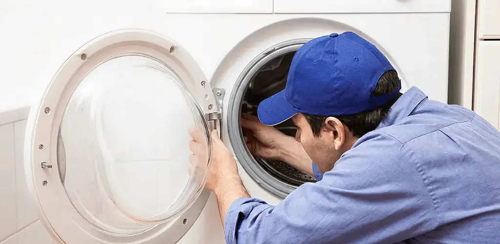 Washing machine repair handyman inspecting a front-load washer drum in Oklahoma City, OK