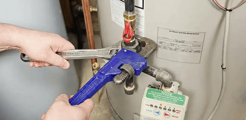 Water heater repair technician tightening the shutoff valve and supply line in Oklahoma City, OK